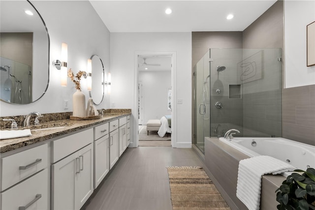 bathroom featuring ceiling fan, vanity, and plus walk in shower