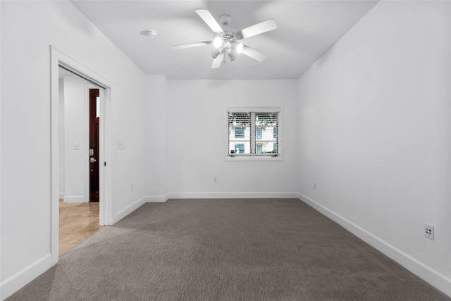 unfurnished room with ceiling fan and dark colored carpet