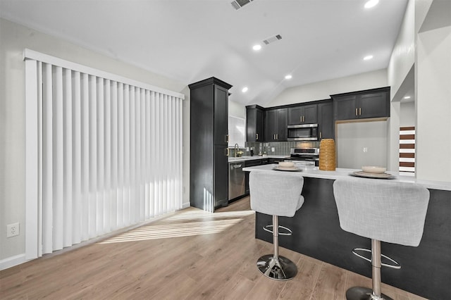 kitchen with a kitchen breakfast bar, stainless steel appliances, light hardwood / wood-style flooring, and a wealth of natural light