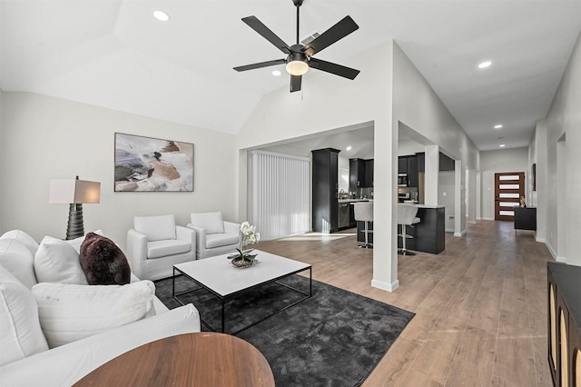 living room with hardwood / wood-style floors, vaulted ceiling, and ceiling fan