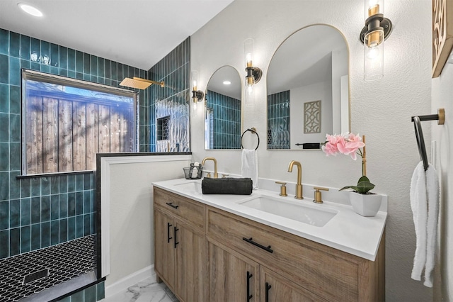 bathroom with a tile shower and vanity