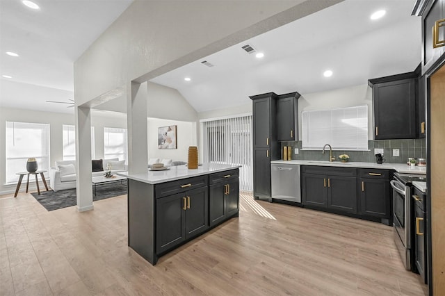 kitchen with stainless steel appliances, sink, light hardwood / wood-style flooring, a center island, and lofted ceiling