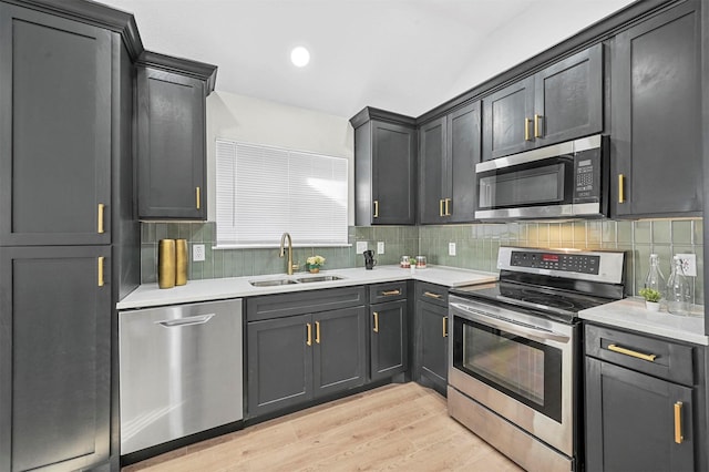 kitchen with light wood-type flooring, stainless steel appliances, backsplash, and sink