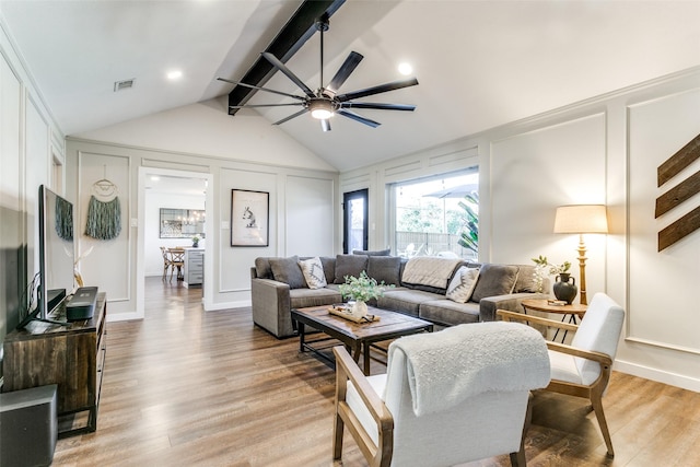 living room with vaulted ceiling with beams, ceiling fan, and light wood-type flooring