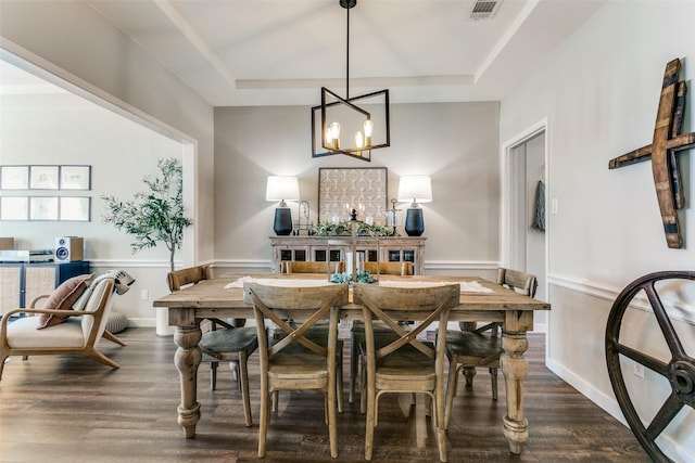 dining room with a raised ceiling, dark hardwood / wood-style floors, and a notable chandelier