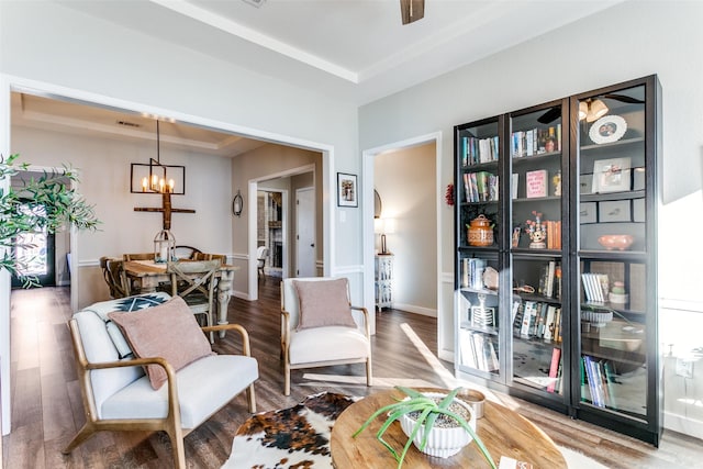 sitting room with hardwood / wood-style floors, a notable chandelier, and a raised ceiling