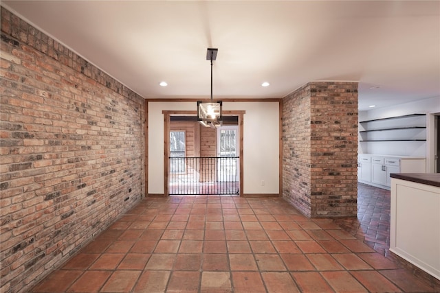 unfurnished dining area with crown molding and brick wall