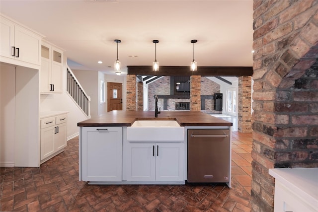 kitchen featuring wood counters, brick wall, sink, decorative light fixtures, and white cabinets