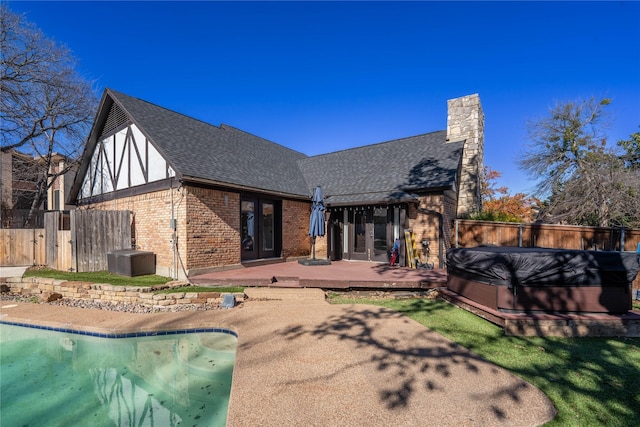 back of property with a swimming pool with hot tub and a patio