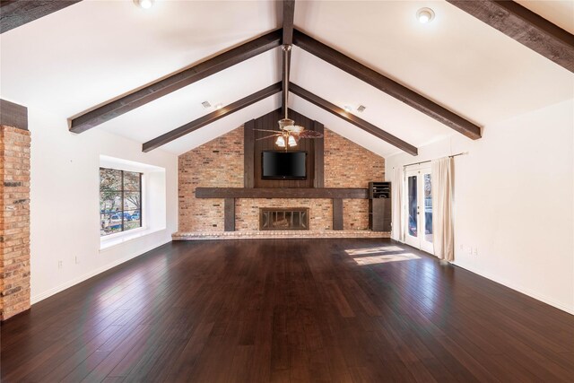 unfurnished living room featuring ceiling fan, vaulted ceiling with beams, brick wall, a fireplace, and hardwood / wood-style flooring