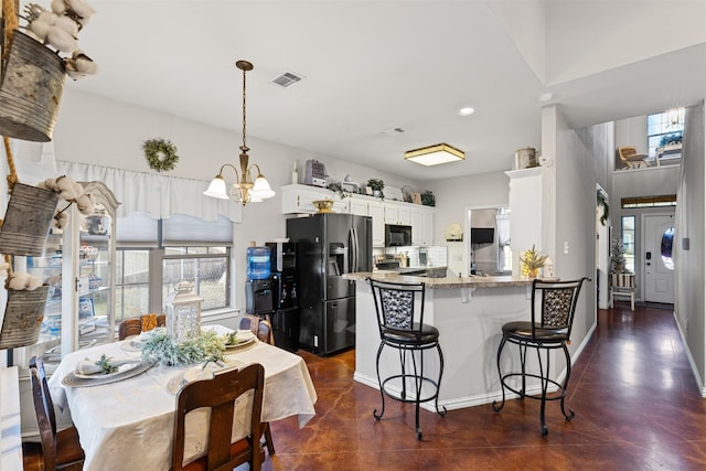 kitchen featuring an inviting chandelier, light stone counters, kitchen peninsula, white cabinets, and appliances with stainless steel finishes