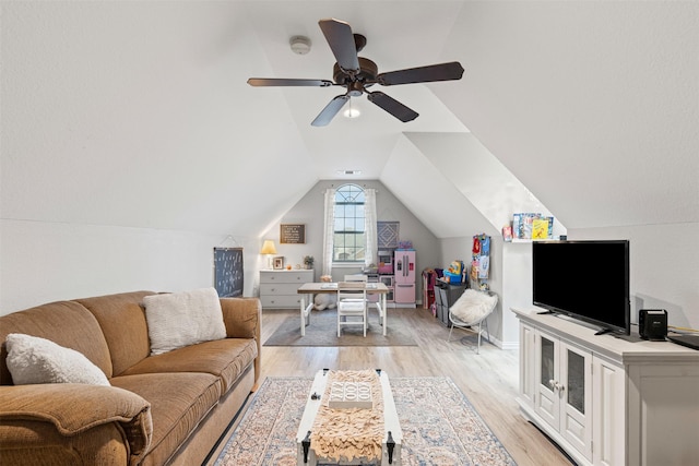 living room with ceiling fan, light hardwood / wood-style floors, and vaulted ceiling