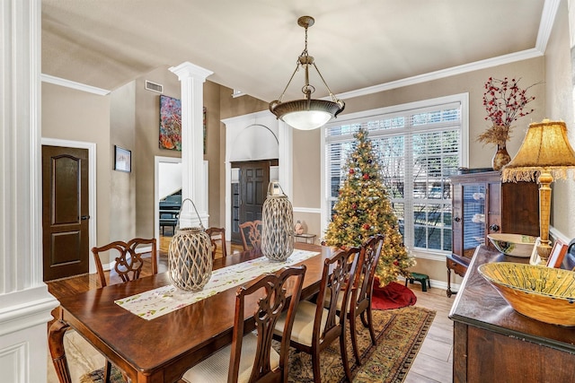 dining space featuring ornate columns, crown molding, and light hardwood / wood-style floors