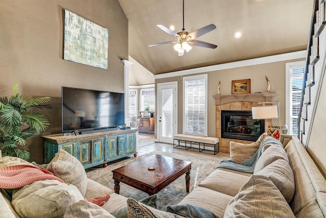 living room featuring a tile fireplace, light wood-type flooring, high vaulted ceiling, and ceiling fan