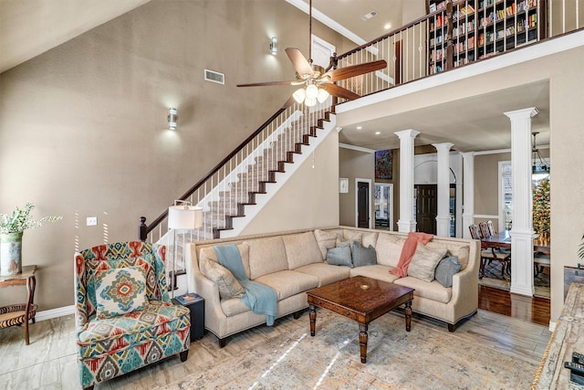 living room with hardwood / wood-style floors, a towering ceiling, ornate columns, and crown molding