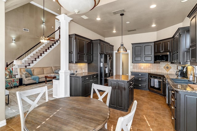 kitchen with sink, hanging light fixtures, a kitchen island, stainless steel appliances, and decorative columns