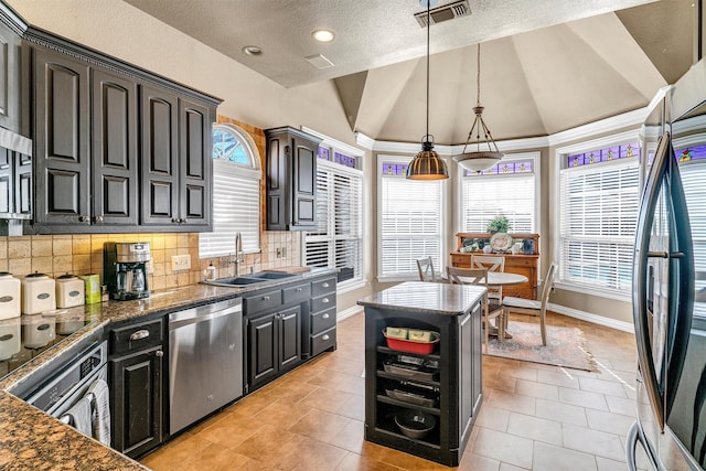 kitchen featuring sink, decorative light fixtures, lofted ceiling, light tile patterned flooring, and appliances with stainless steel finishes