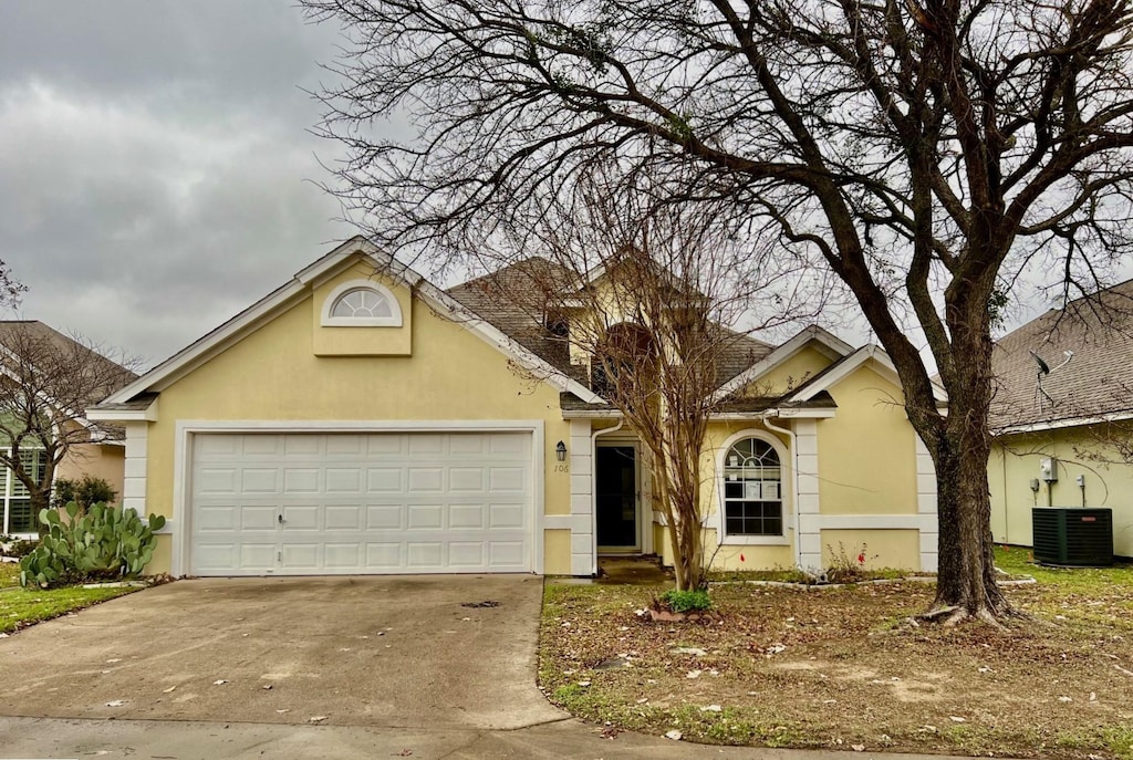 view of front of home with a garage and central air condition unit