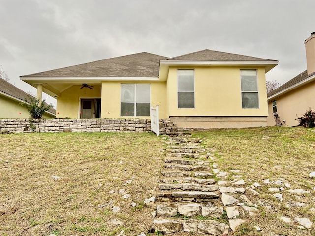 rear view of house featuring a lawn and ceiling fan