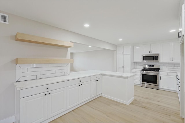 kitchen featuring kitchen peninsula, appliances with stainless steel finishes, and white cabinetry