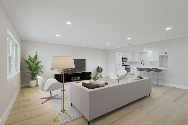 living room featuring crown molding, sink, and light hardwood / wood-style floors