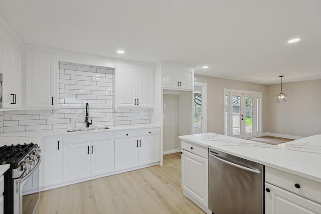 1016 Cavender Dr, Hurst, TX 76053 - kitchen featuring white cabinets, appliances with stainless steel finishes, a sink, light wood-style flooring, and backsplash