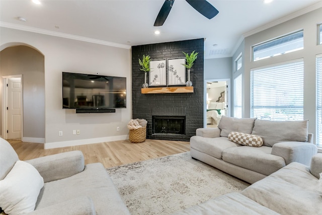 living room featuring a fireplace, hardwood / wood-style floors, ceiling fan, and ornamental molding