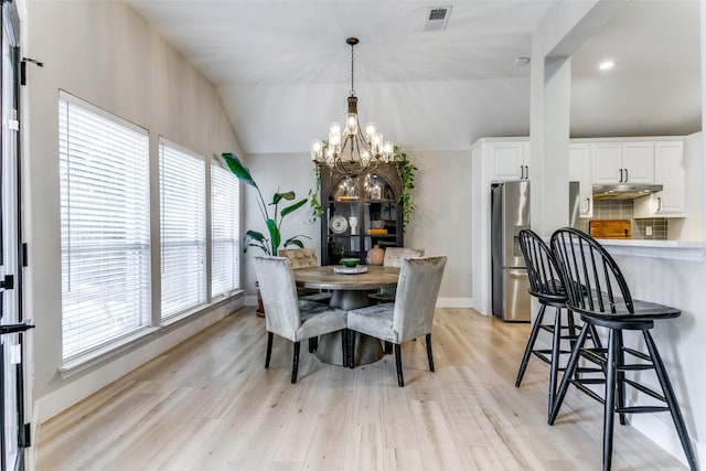 dining room with light hardwood / wood-style floors, an inviting chandelier, and lofted ceiling