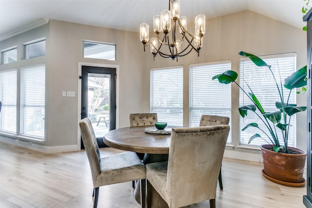 dining area with light hardwood / wood-style floors, an inviting chandelier, and lofted ceiling