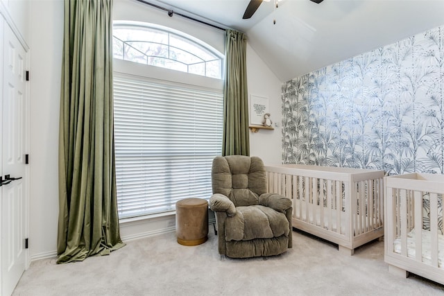 carpeted bedroom featuring ceiling fan, lofted ceiling, a crib, and multiple windows