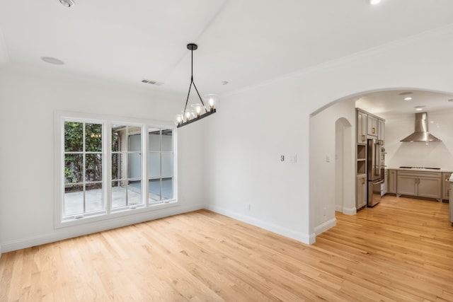 unfurnished dining area with an inviting chandelier, light wood-type flooring, and ornamental molding