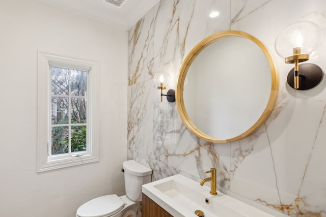 bathroom featuring toilet, vanity, and ornamental molding