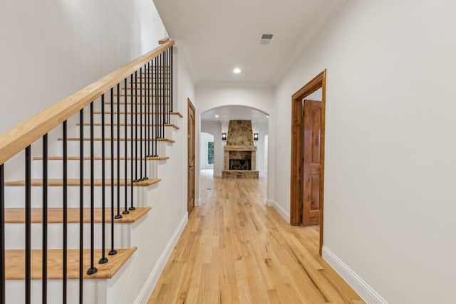 hallway with light wood-type flooring and ornamental molding