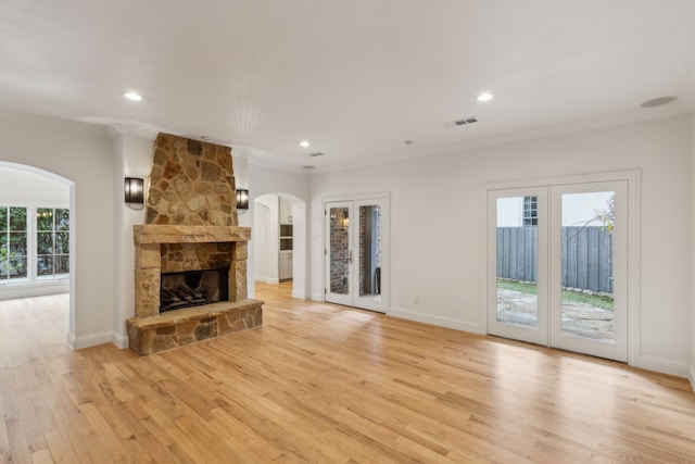 unfurnished living room with light hardwood / wood-style floors, french doors, crown molding, and plenty of natural light