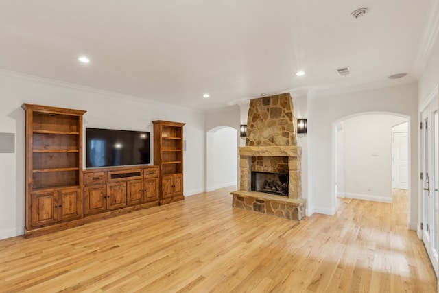 unfurnished living room with light hardwood / wood-style floors, a stone fireplace, and crown molding