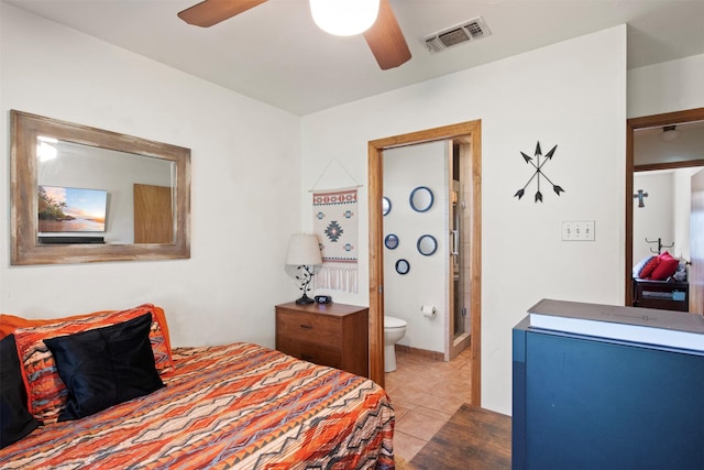 bedroom featuring light tile patterned floors, ensuite bathroom, and ceiling fan