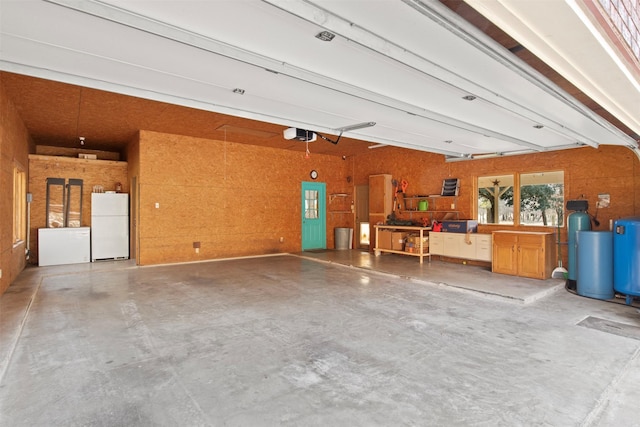 garage featuring wooden walls, white fridge, and a garage door opener