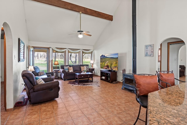 living room featuring high vaulted ceiling, a wood stove, and light tile patterned flooring