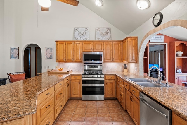 kitchen featuring backsplash, stainless steel appliances, light stone counters, and sink