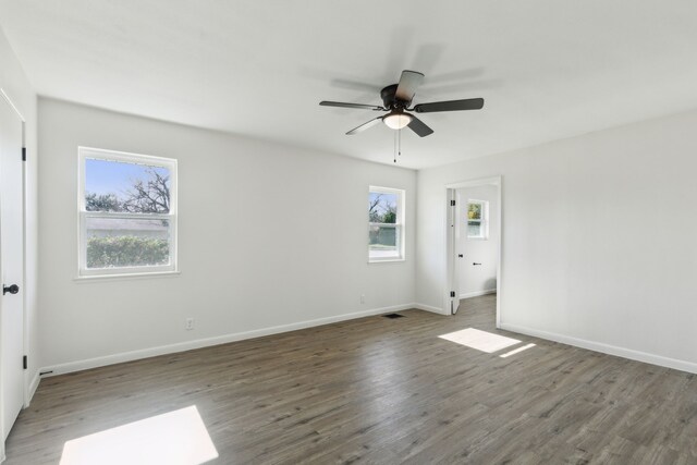 unfurnished bedroom with multiple windows, ceiling fan, dark hardwood / wood-style flooring, and multiple closets