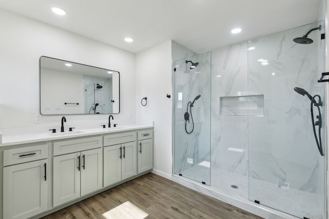 bathroom with hardwood / wood-style floors, vanity, and a tile shower