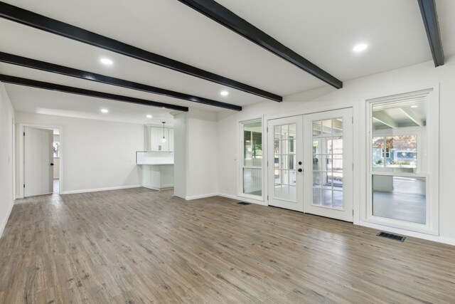 empty room with beam ceiling and light hardwood / wood-style floors