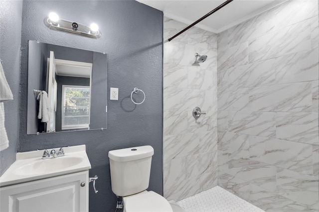 bathroom with toilet, a tile shower, crown molding, and vanity