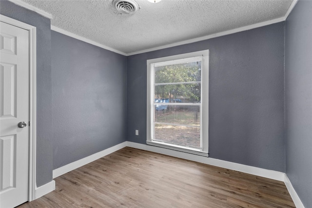 spare room with crown molding, a textured ceiling, and light wood-type flooring