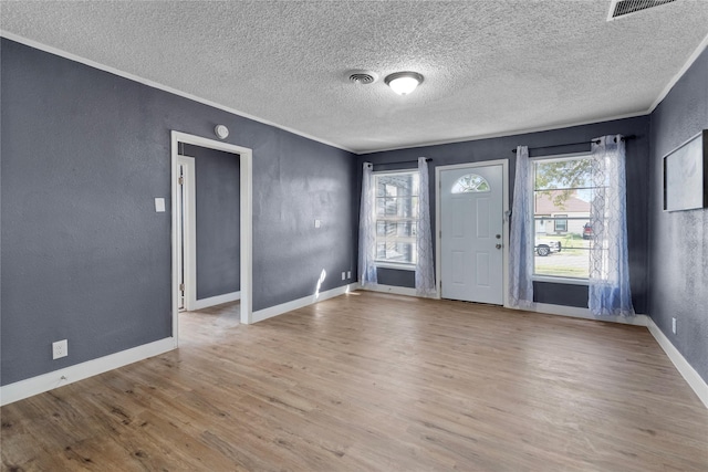 unfurnished room featuring a textured ceiling, light hardwood / wood-style floors, and crown molding