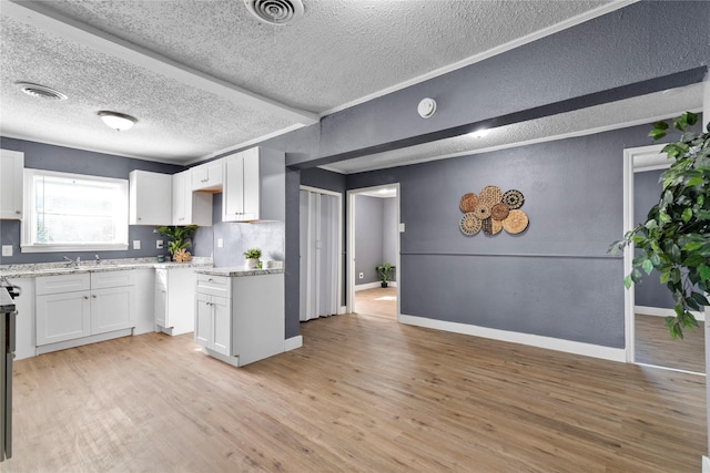 kitchen with tasteful backsplash, white cabinetry, a textured ceiling, and light wood-type flooring