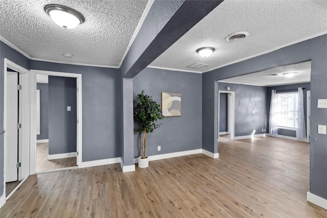 empty room featuring wood-type flooring, ornamental molding, and a textured ceiling