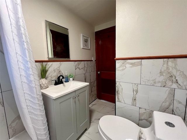 bathroom featuring toilet, vanity, tile walls, and a shower with shower curtain