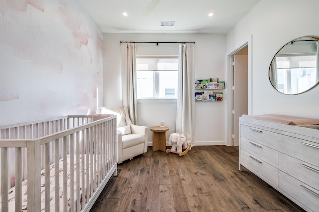 bedroom with dark hardwood / wood-style floors and a nursery area