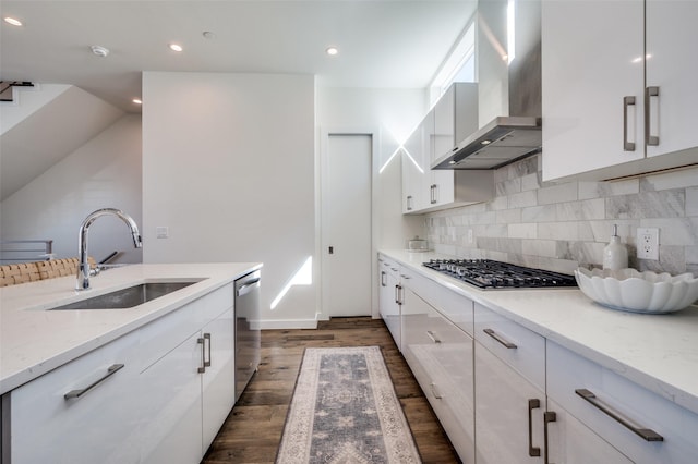 kitchen featuring white cabinetry, sink, wall chimney range hood, light stone counters, and appliances with stainless steel finishes